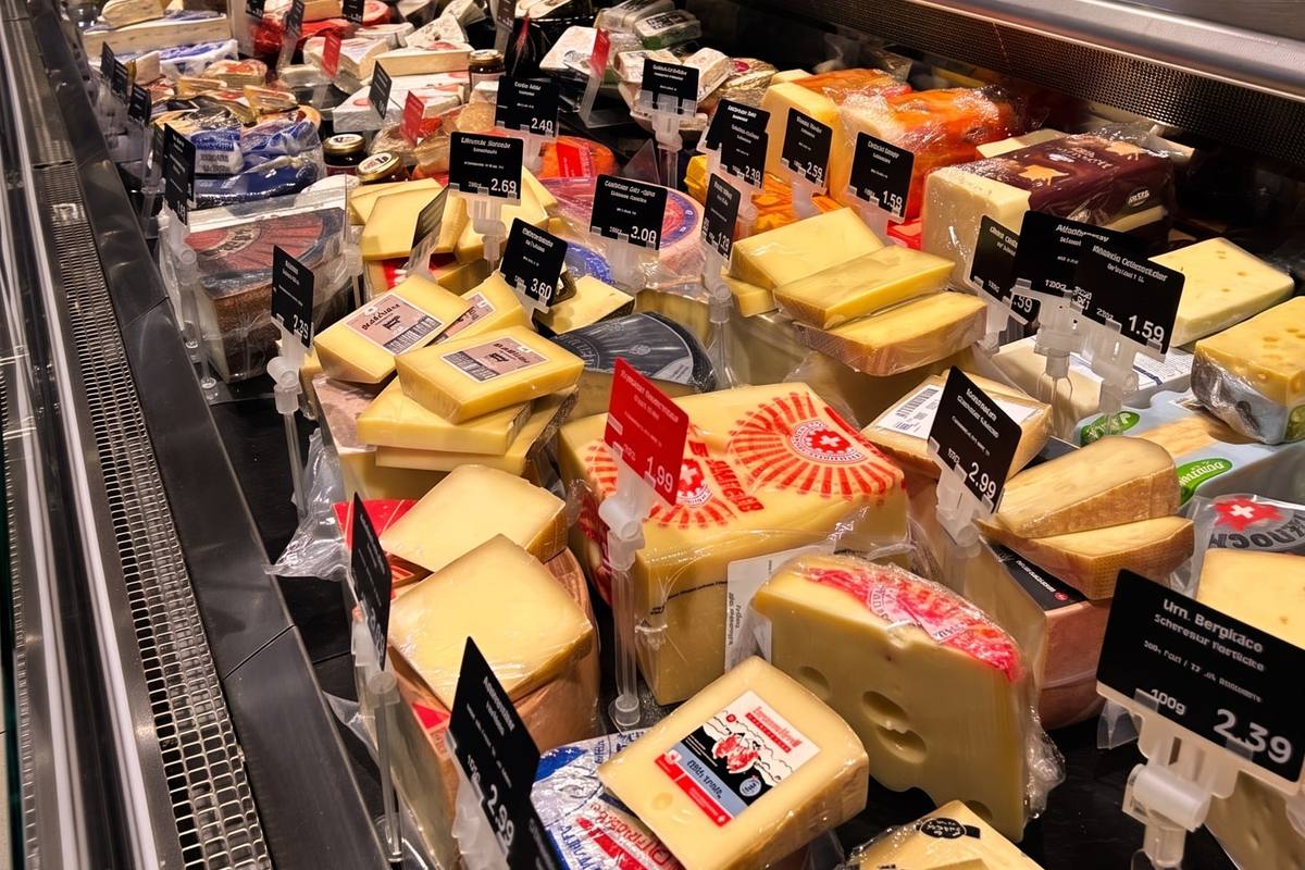 Die Käseauslage: Hart- und Weichkäse am Stück und geschnitten in der gekühlten Vitrine, dahinter Waage und Terminal der Bedientheke. (KI-modifizierte Darstellung)